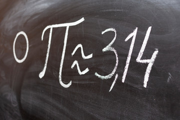 number pi handwritten with white chalk on a blackboard