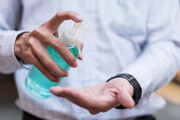 man hand using wash hand sanitizer gel dispenser, against Novel coronavirus or Corona Virus Disease (Covid-19) at public Indoor. Antiseptic, Hygiene and Healthcare concept