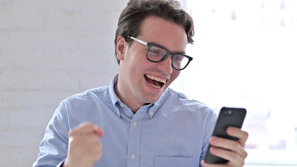 Portrait of Young Man Celebrating Success on Smartphone