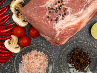 Raw pork meat on a marble board with spices and vegetables