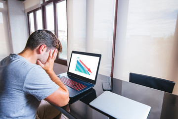 Young man desperate in front of computer with coronavirus stock crash on the screen