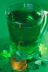 Saint Patricks day backdrop with bear cup with ale, stack of chocolate coins, green four-leafed paper clovers