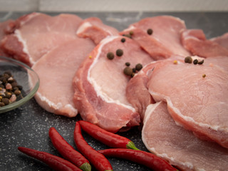 Raw pork steaks on a marble board with spices