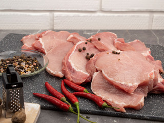 Raw pork steaks on a marble board with spices