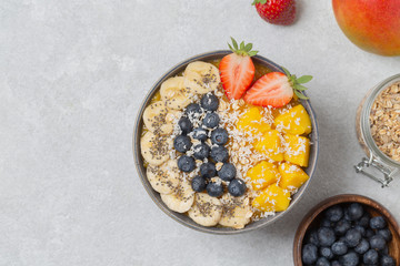 Healthy smoothie bowl with mango, strawberry, blueberry, banana, Chia seeds and granola. Healthy vegan diet food concept. Top view