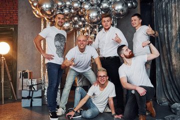 Group of cheerful men standing together in christmas decorated room and posing for a camera