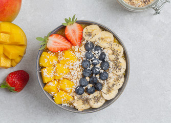 Healthy smoothie bowl with mango, strawberry, blueberry, banana, Chia seeds and granola. Healthy vegan diet food concept. Top view