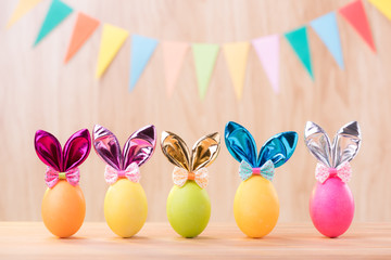 Happy Easter day colorful eggs with bunny ears on wooden floor blurred celebrate banner party flags with copy space