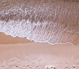 Aerial view of sandy beach and sea with waves