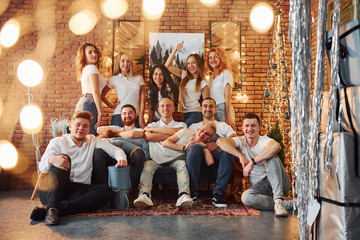 Smiling young people celebrating New Year in cozy christmas decorated room together