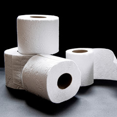 Rolls of white toilet paper lie on a black background