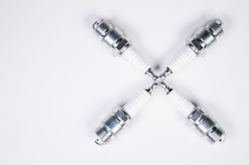 Subject shooting on a gray background. new four spark plugs, spare parts for a gasoline engine. The concept of new auto parts and maintenance