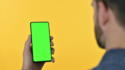 Rear View of Designer Looking at Smartphone with Chroma Screen, Yellow Background
