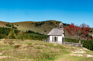 Fototapeta na wymiar Autumn landscape, Styria, Austria - The old beautiful chapel on the Postalm, on an autumn day in golden October with blue sky.