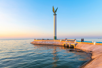 The pier of Campeche city illuminated at sunset with the angel of miscegenation (indigenous and Spanish) and its waterfront promenade by the Gulf of Mexico, Campeche state, Mexico.