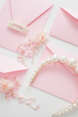 Wedding background, white with space for text, decorated with pink invitations, pearl jewelry, with copy space. Concept wedding flatly.