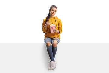 Young woman sitting on a panel and eating popcorn