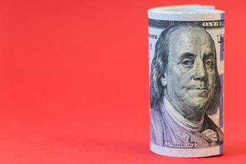 roll of 100 dollar banknotes on red background