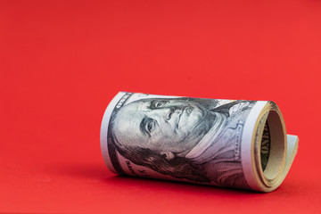 roll of 100 dollar banknotes on red background