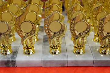 a lot of gold cups are on the table for awarding the winners of spot competitions close up