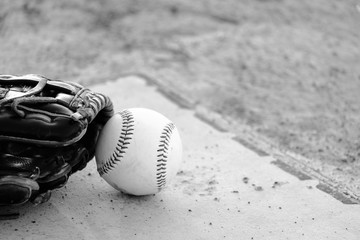 Baseball glove and ball on game field in black and white.