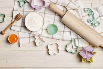 Obraz na płótnie Canvas Baking utensils and ingredients. Colorful silicone cooking utensils, rolling pin, cookie mold,. cupcake cases and sugar sprinkling on a white wooden background. Easter concept.