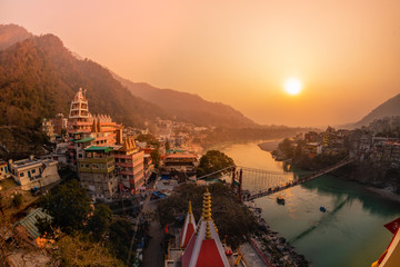 View of Ganga river embankment, Lakshman Jhula bridge and Trimbakeshwar Temple in Rishikesh, Uttarakhand, India - obrazy, fototapety, plakaty
