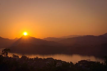 Glorious sunset over hazy mountains by the Mekong river. View from Mount Phou Si, in Luang Prabang, Laos.