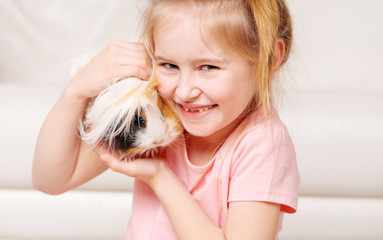 Cute little girk having a lot of fun with peruvian guinea pig