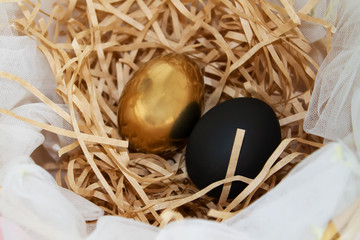 Golden and black  easter egg lying in beige paper filler