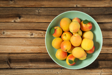 Sweet apricots in plate on brown wooden table