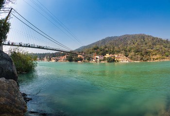 View of Ganga river embankment, Lakshman Jhula bridge and Trimbakeshwar Temple in Rishikesh, Uttarakhand, India