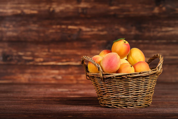 Sweet apricots in basket on brown wooden table