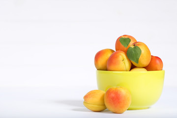 Sweet apricots in bowl on white background