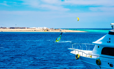 Male sportsman windsurfing and ship in blue sea