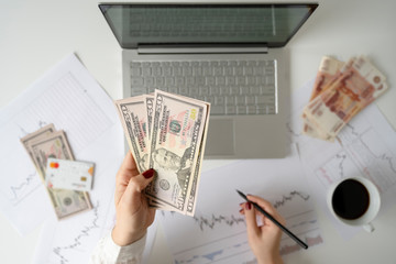 Woman freelancer. pack of banknotes fifty U.S. dollars, five thousand rubles, credit card and...