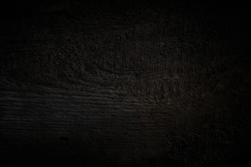 Empty wooden table on a background of dark blurred wall, empty space for product above..