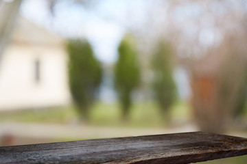 Fototapeta premium An empty wooden tabletop on a window pane and abstract green blur from the garden with a view of the yard, can be used to display or assemble your products (or products).