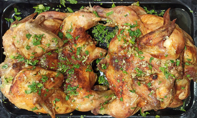 Homemade baked chicken with herbs and garlic on a black pan