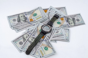 Wristwatch lies on background of scattered American dollars