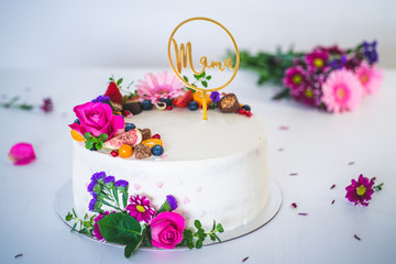 Sweet white cheesecake torte with fresh fruits and rose flowers for mother mama on white wooden table