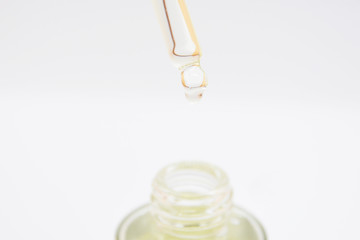 drops of collagen serum moisturizer face in a transparent yellow bottle soft light background. Skin...