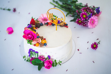 Sweet white cheesecake torte with fresh fruits and rose flowers for mother mama on white wooden table