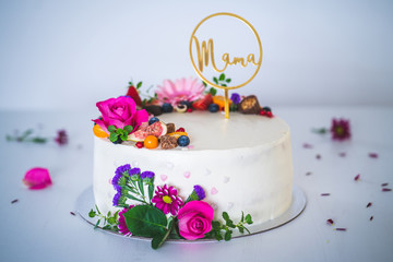 Sweet white cheesecake torte with fresh fruits and rose flowers for mother mama on white wooden table