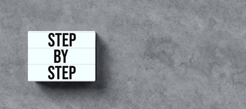 lightbox with message STEP BY STEP on concrete background