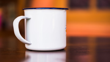 Classic enameled cup on wooden table. Antique rustic coffee cup on a vintage, brown smooth teak wood surface.