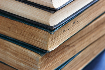 Old books with frayed covers on a dark table.