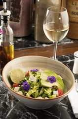 Fresh summer a bowl of salad with avocado, cheese and white wine