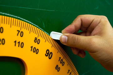 Yellow protractor for the school Board. The teacher draws a circle with white chalk. School drawing...