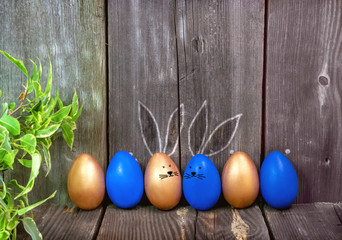 Happy Easter greeting card.Blue and gold eggs with cute Bunny ears on a rustic wooden background.Festive decoration.Spring holiday. Banner, Billboard for sale in the store, website.copy space.